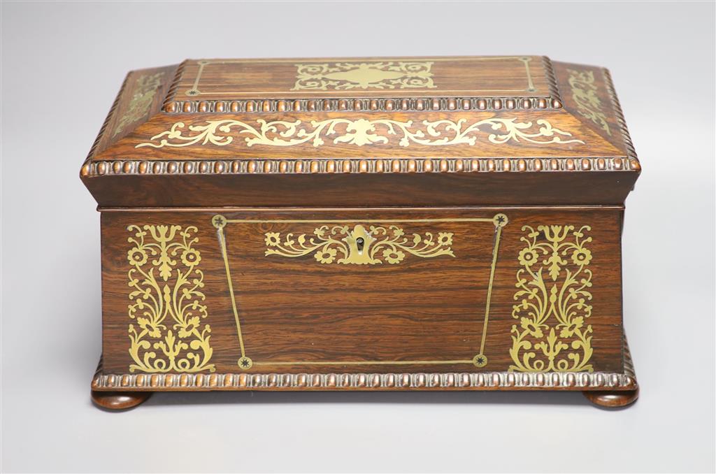 A Regency rosewood and cut brass inlaid sarcophagus shaped tea caddy, (mixing bowl restored), length 33cm